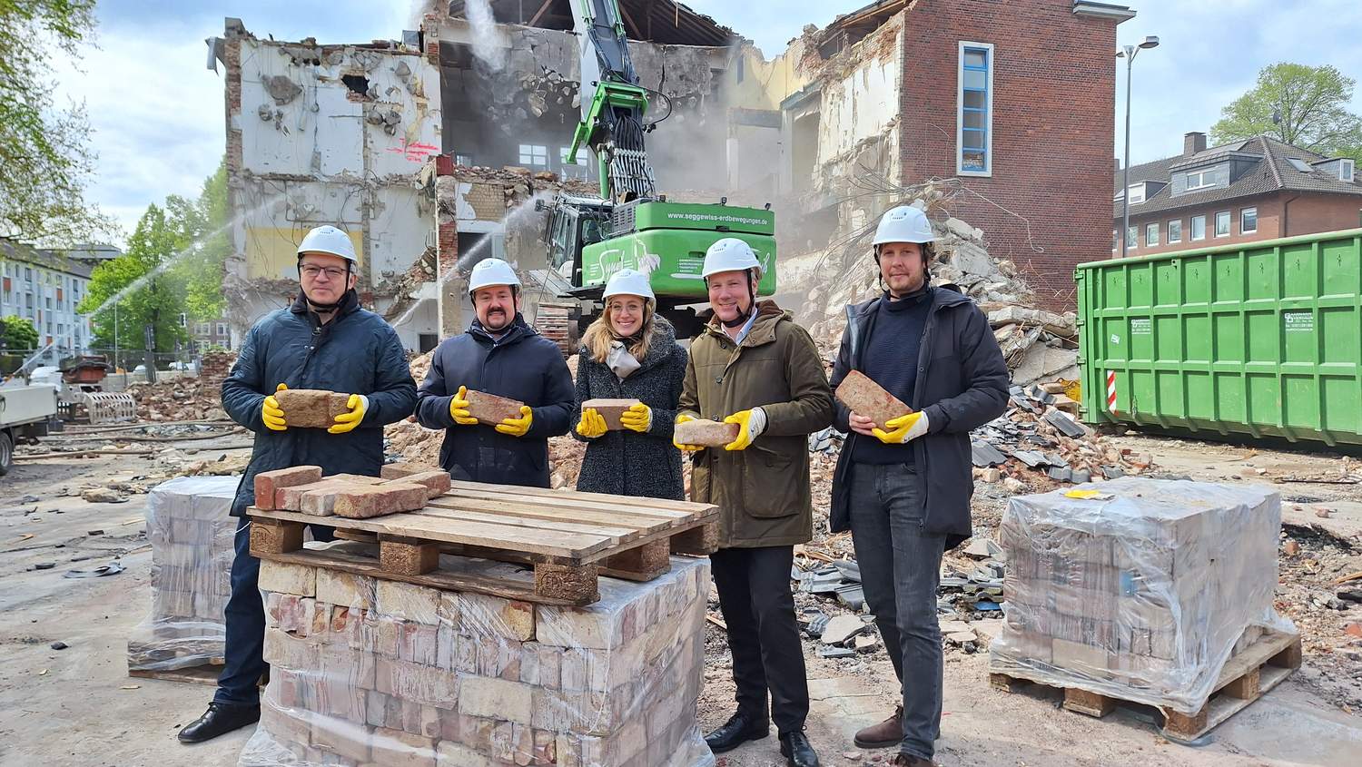 Symbolträchtiger Brückenschlag von der Vergangenheit in die Zukunft Die Projektverantwortlichen vor Ort mit den Ziegelsteine, die im Neubau wieder zum Einsatz kommen werden